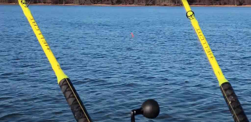Bright-yellow Hellcat rods from Catch The Fever stand out against calm blue water, with a single bobber floating nearby.